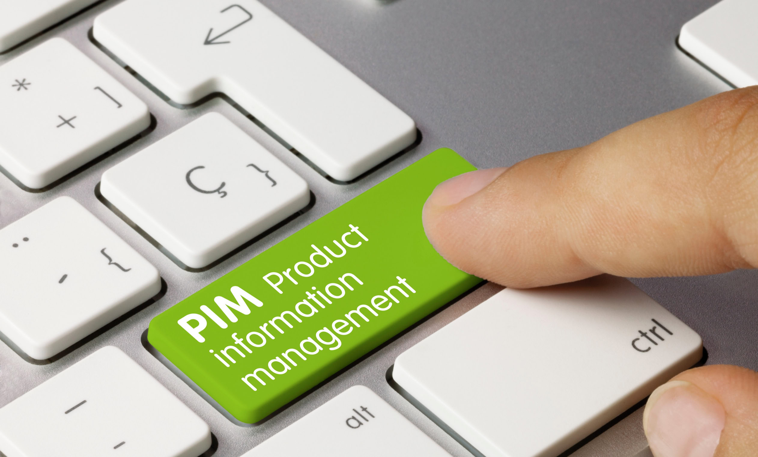 Finger drückt eine grüne Taste auf einer Computertastatur mit der Aufschrift "PIM Product Information Management".